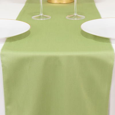 Green table runner with white plates and glasses on a dining table.