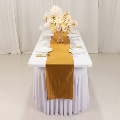 Elegant gold table runner on a white table with floral centerpiece.