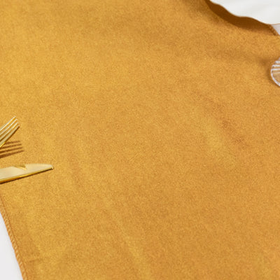 Golden table runner on a white surface with elegant cutlery.