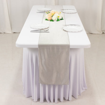 Elegant table setting with a floral centerpiece and silver runner.