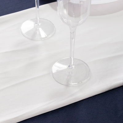 Two elegant champagne flutes on a white table runner.