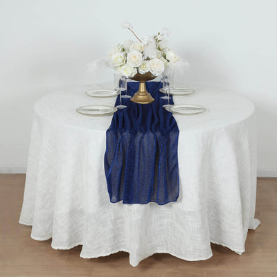 Elegant table setting with navy runner, white tablecloth, and floral centerpiece.