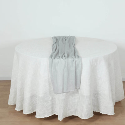 Gray table runner draped on a round white table.