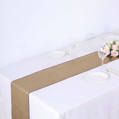 Brown table runner on a white table setting with plates and glasses.