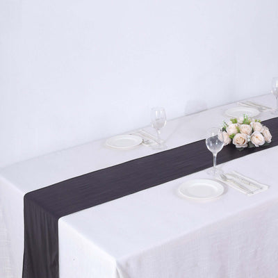 Black table runner on a white table with floral centerpiece and dinnerware.