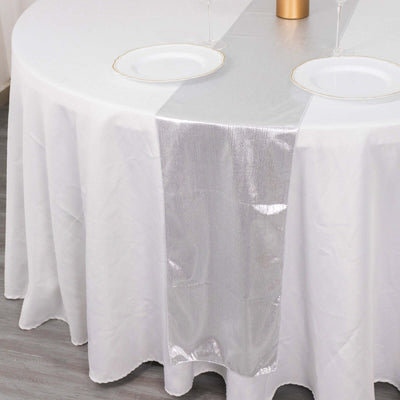 Elegant silver table runner on a white round table setting.