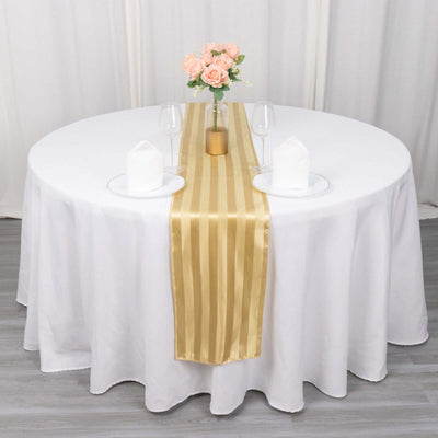 Elegant round table set with a gold striped runner and floral centerpiece.