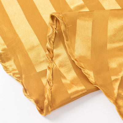 Golden satin fabric with striped pattern, showcasing smooth texture and sheen.