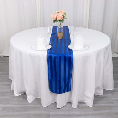 Blue striped table runner on a round table set with flowers and glassware.