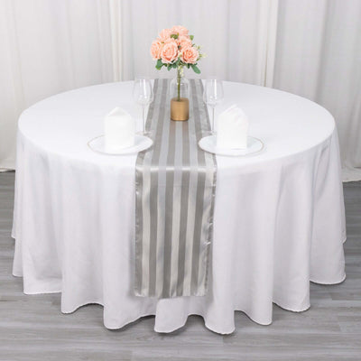 Elegant gray striped table runner on a round dining table with floral centerpiece.