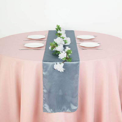 Gray satin table runner with artificial flowers on a pink tablecloth.