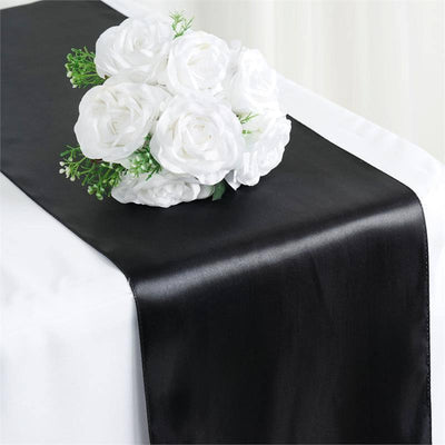 Black satin table runner with white rose arrangement