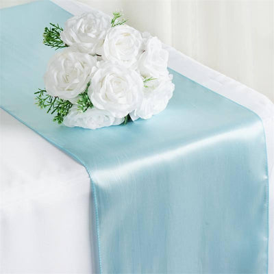 Light blue satin table runner with white rose bouquet on top.