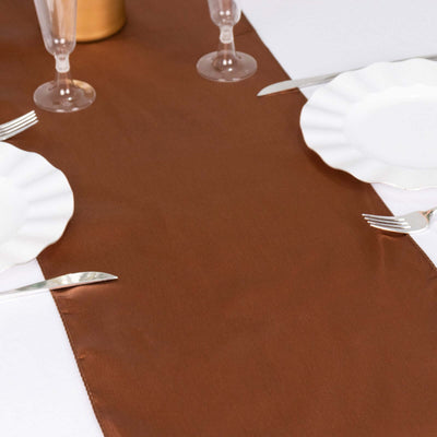 Brown table runner styled with white plates and glassware on a dining table.