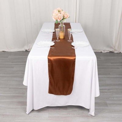 Elegant dining table set with a brown satin runner and floral centerpiece.