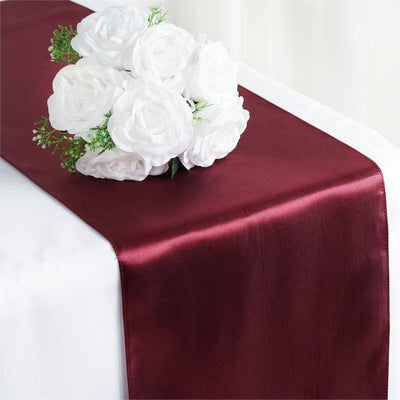 Burgundy satin table runner with white floral centerpiece