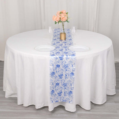 Round table set with a white tablecloth, blue floral runner, and floral centerpiece.