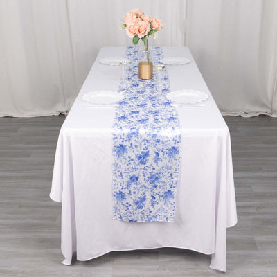 Floral table runner on a dining table with plates and a vase of roses.