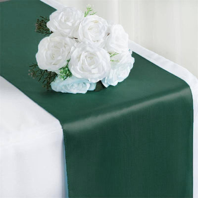 Green table runner with white rose bouquet on a plain table.