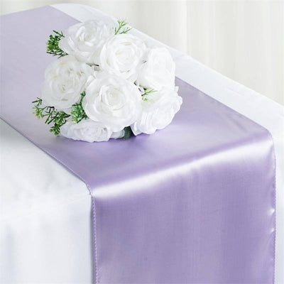 Purple satin table runner with white rose bouquet on a table.
