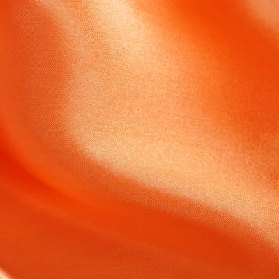 Close-up of smooth orange satin fabric texture.
