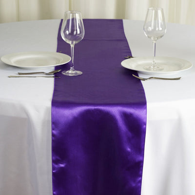Purple satin table runner on a dining table with plates and glasses.