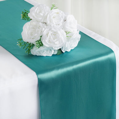 Teal satin table runner with white rose bouquet arrangement.