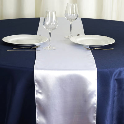 Elegant table setting with navy blue tablecloth and silver runner.