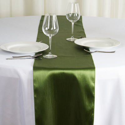 Green satin table runner on a white table setting with plates and glasses.