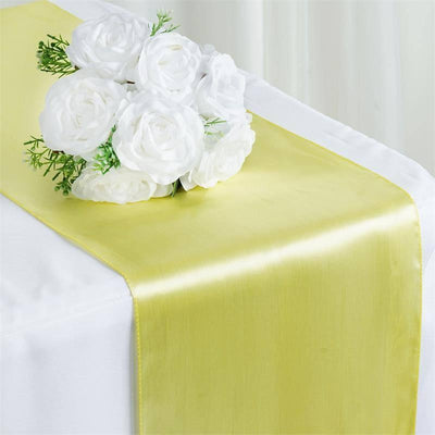 Yellow satin table runner with white rose bouquet on a white table.