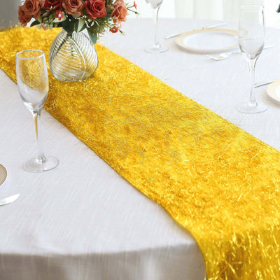 Gold glitter table runner on a white table with glassware and floral centerpiece.