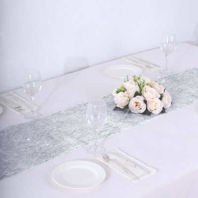 Silver table runner with pink roses centerpiece on a dining table.