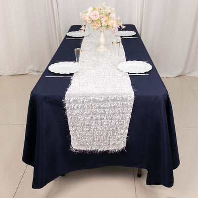 Elegant silver table runner on a navy tablecloth with decorative plates and flowers.
