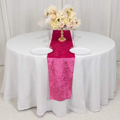 Round table set with a pink runner and floral centerpiece.