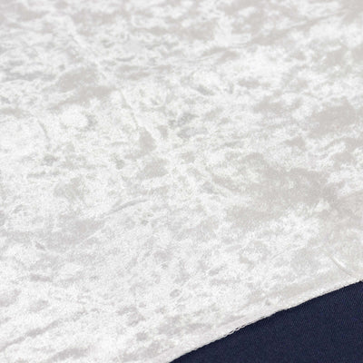 Textured white fabric with a soft sheen and subtle patterns.