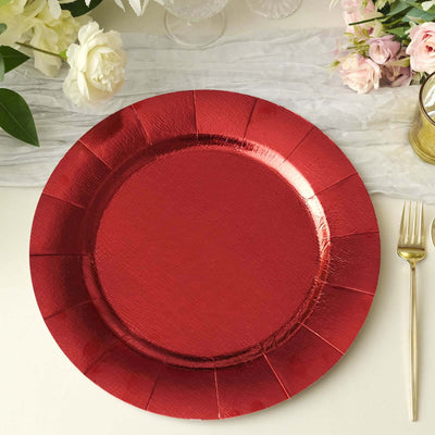 Red decorative plate on a table setting with flowers and cutlery.