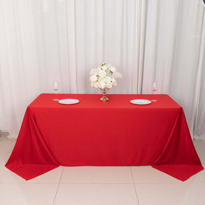 Red tablecloth draped elegantly over a table with floral centerpiece and dinnerware.