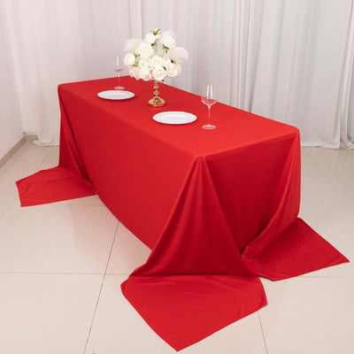 Red tablecloth draped elegantly on a table with floral centerpiece and dinnerware.