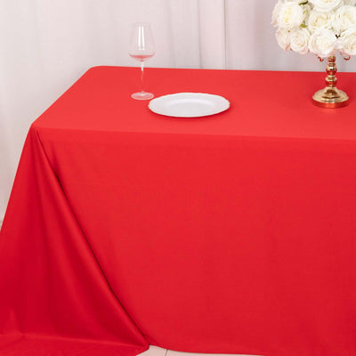Red tablecloth draped over a table with a glass and decorative flowers.