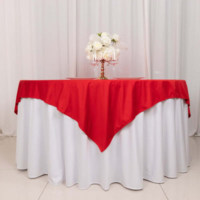Red tablecloth draped over a white table with floral centerpiece.
