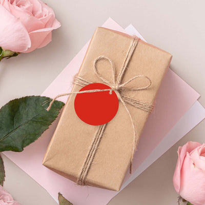 Gift wrapped in brown paper with a red tag, surrounded by pink roses.
