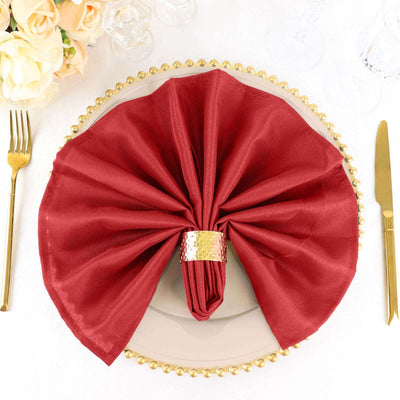 Elegant red napkin folded on a decorative plate with a golden napkin ring.