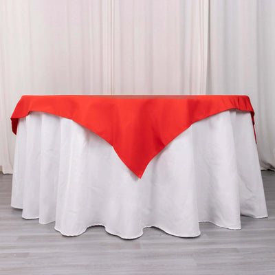 Red tablecloth draped over a white table in a studio setting.