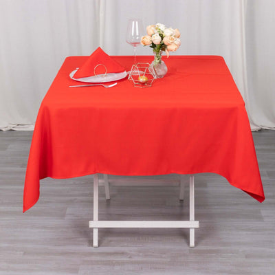 Red tablecloth set with napkin and glass on a dining table.