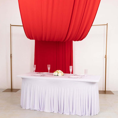 Elegant table setup with red drapery and floral centerpiece for events.