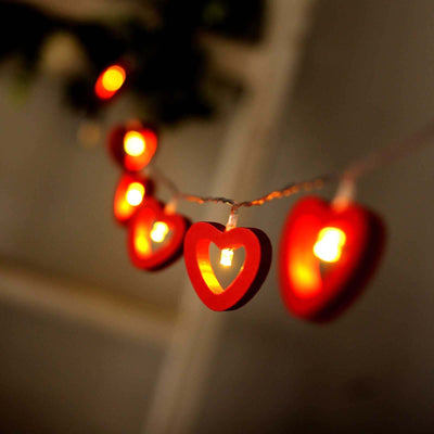 Red heart-shaped string lights glowing softly in a cozy setting.