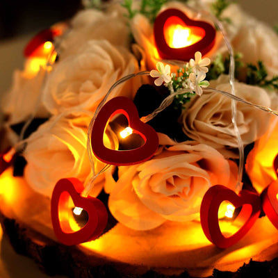 Heart-shaped fairy lights on a floral arrangement with warm glow.