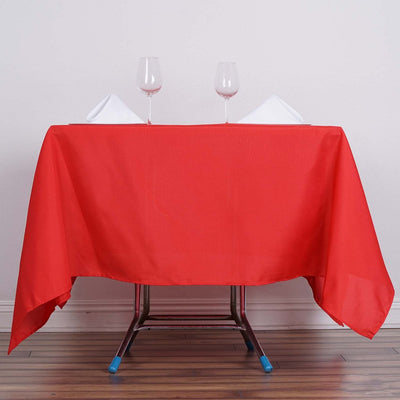 Red tablecloth with wine glasses and folded napkins on a table
