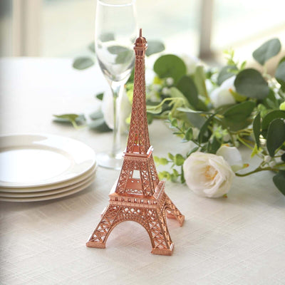 Rose gold Eiffel Tower replica on a table with flowers and plates.