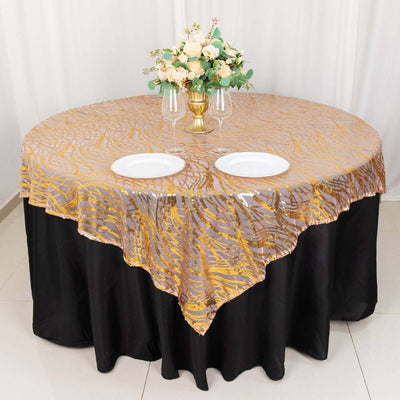 Elegant round tablecloth with gold pattern on black table, set for dining.